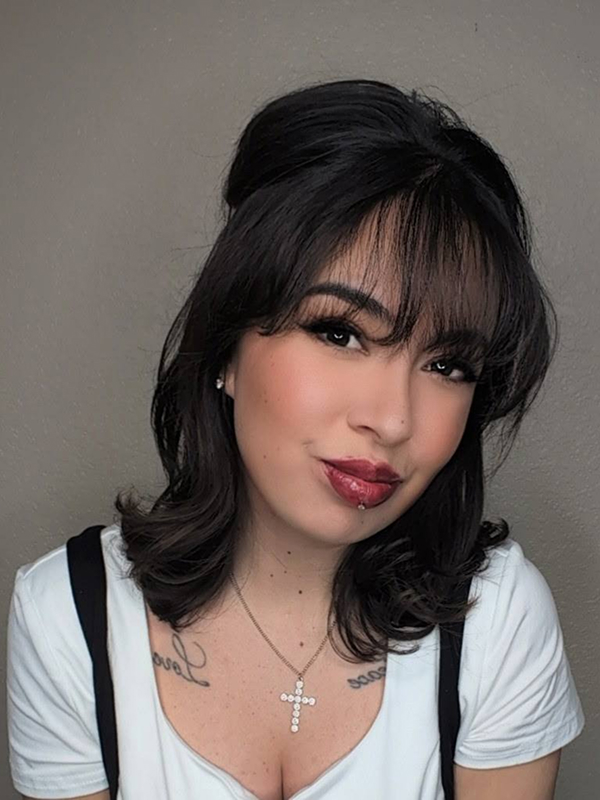 Person with dark hair and necklace