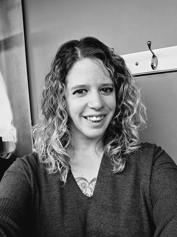 Person with curly hair and tattoo