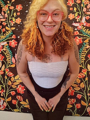 Person with curly hair and tattoos.