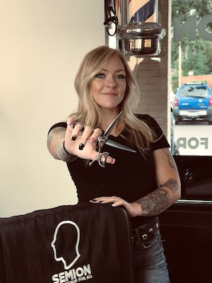 Person holding scissors in salon.