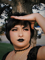 Person posing outdoors with hand raised.